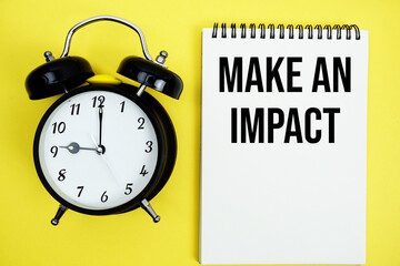 Make An Impact text with alarm clock flat lay on yellow background