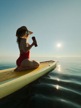 Young woman walking on stand up paddle sup boards by the sea during summer vacation