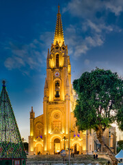 Illuminated facade of the Parish Church in Ghajnsielem, Gozo, at blue hour with Christmas tree