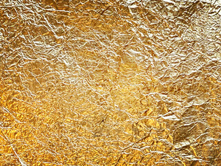 Golden crumpled foil texture background with shiny metallic surface yellow glint luxury decorative paper elegant abstract pattern for greeting card design or premium gift wrapping