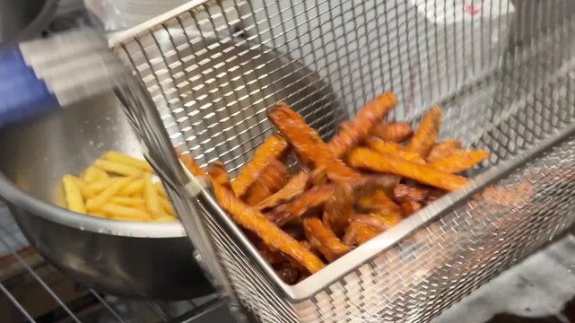 Sweet potato fries and French fries in bowls beside deep fryer with bubbling oil, showcasing the cooking process in a kitchen setting