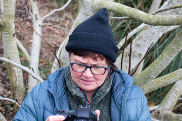 Person checks camera settings in a wooded area