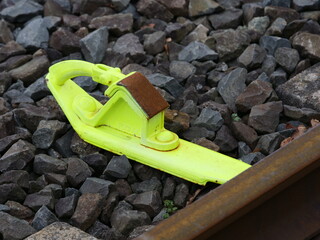 Yellow wheel chock or wheel stop used in the railway industry to secure vehicles against rolling away.