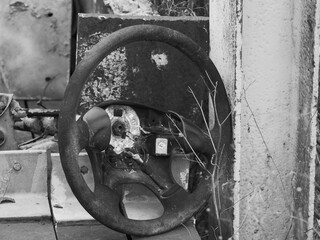 Old, heavily weathered car steering wheel, black and white photo