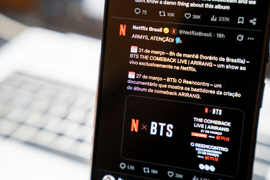 Warsaw, Poland - Feb 3, 2026: A smartphone screen displaying a Netflix tweet about BTS The Comeback Live event with promotional details in Brazilian Portuguese.