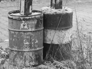 old oil barrels filled with concrete and used as supports, black and white picture