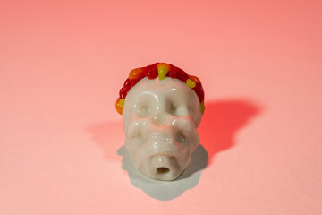 A carved bone skull on a pinkish background.