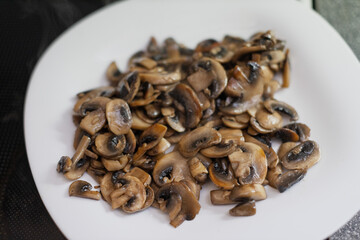 Obraz premium A pile of sliced sauteed mushrooms rests on a white plate.