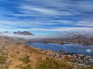 View of the waterfront infrastructure in Tasiilaq, Greenland. The clip shows the port area with shipping containers, fishing boats, and local housing, highlighting life in a remote Arctic community 