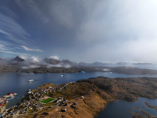 View of the waterfront infrastructure in Tasiilaq, Greenland. The clip shows the port area with shipping containers, fishing boats, and local housing, highlighting life in a remote Arctic community 