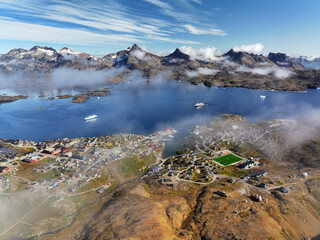 View of the waterfront infrastructure in Tasiilaq, Greenland. The clip shows the port area with shipping containers, fishing boats, and local housing, highlighting life in a remote Arctic community 