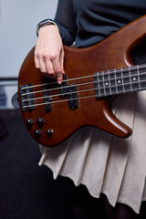 Fototapeta premium Female bassist rehearsing. Female musician with bass guitar. Female performer practicing in dim studio lighting. Female bassist preparing for performance in moody rehearsal space