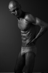 Naklejka premium Athletic man posing in a black and white photograph, highlighting his toned physique and strong silhouette. An artistic representation of strength and confidence.