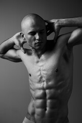 Muscular man posing in a black and white photo, showcasing strength and emotion through dramatic lighting and contrasting shadows. Perfect for fitness and art themes.