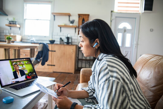 Woman on video call taking notes at home