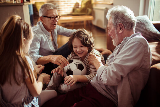 Grandparents and children playing with soccer ball at home