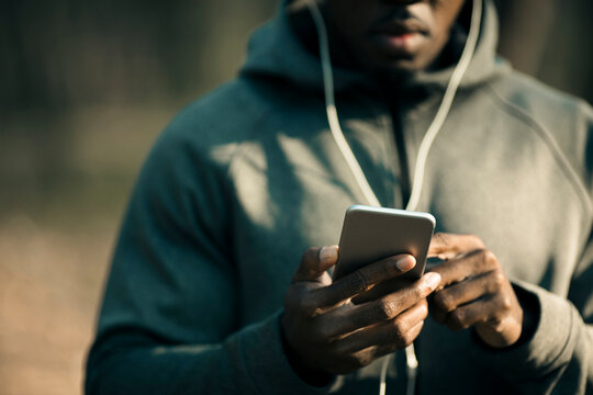 Man using smartphone with earphones outdoors in park