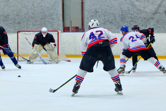 A hockey player attacks an opponent's goalkeeper