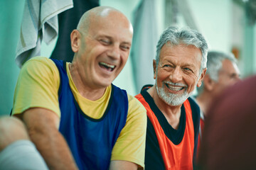 Two senior men laughing on bench in indoor gym