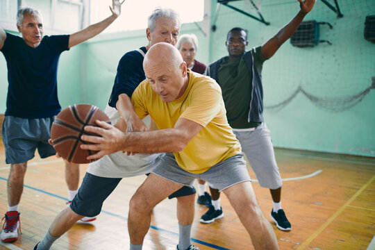 Senior men playing basketball in indoor gym