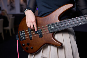 Fototapeta premium Female bassist rehearsing. Female musician with bass guitar. Female performer practicing in dim studio lighting. Female bassist preparing for performance in moody rehearsal space