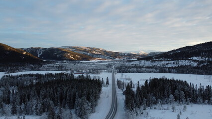 Winter road winding through snow-covered forests and mountains in Norway