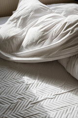 Closeup of wrinkled white pillow and blanket in soft light