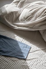 Morning light on unmade bed with blue cloth