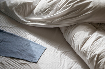Morning light on unmade bed with blue cloth