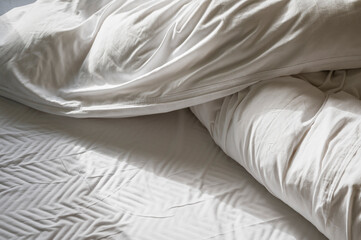 Closeup of wrinkled white pillow and blanket in soft light