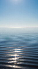 Obraz premium Calm ocean horizon with gentle ripples and sun reflections on a clear day