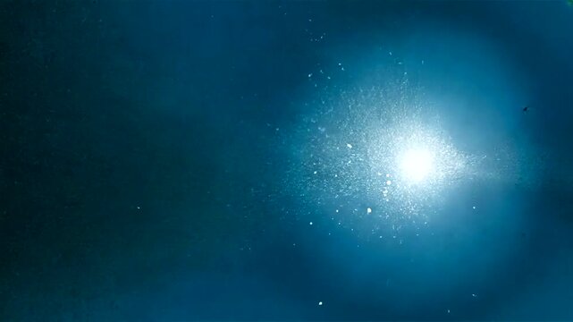 Bright Light Shining in Dark Blue Background with Sparkling Particles.