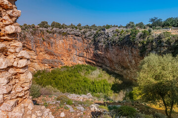 This massive geographical sinkhole near Mersin, Turkey. Presents a dramatic vertical landscape, dropping deep into the earth. The top border of this historical formation reveals ancient stone.
