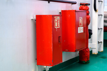 Two bright red emergency boxes are mounted on a green deck of a ship in Russia. They serve vital safety functions while contributing to the vessel's distinct color scheme.