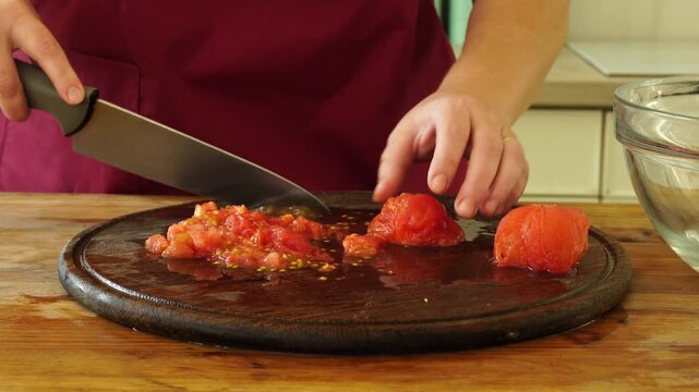 Woman cooking sauce with fresh tomato at the kitchen
