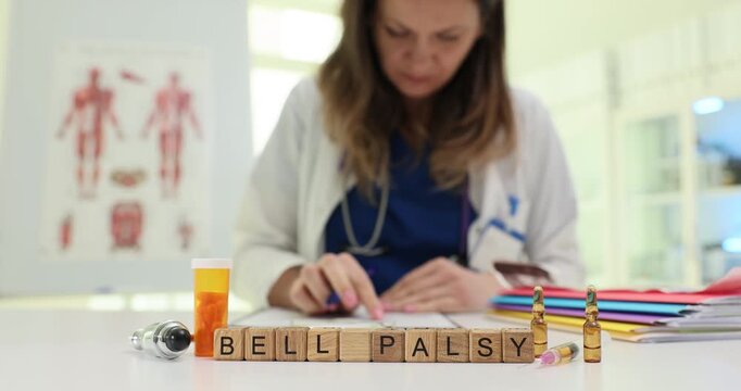 Text Bell Palsy on wooden cubes by examination tool and drugs in clinic. Focused woman doctor researches paralysis on single face side in hospital