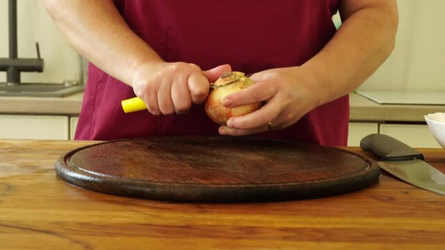 Woman is peeling and cutting onions for cooking
