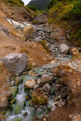 A serene stream winds through rugged rocks and earth, showcasing nature's beauty in Russia's landscape. Clear water gently flows, creating a soothing atmosphere amidst the wilderness.