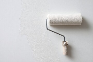 Obraz premium paint roller with white fabric on a wall