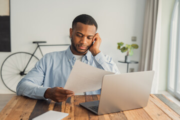 Obraz premium African student guy sit at desk hold papers tasks having difficulties with test, company lawyer read contract terms and detail feels discontented, received bad news from bank unpleasant letter concept