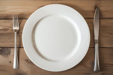 White plate on wooden table with fork and knife arranged neatly for dining without any food present