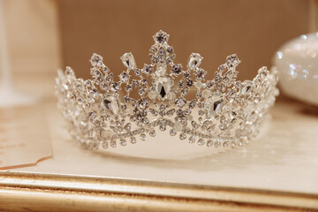 Close-up of a luxurious silver bridal tiara with diamonds and crystals, elegant wedding hair accessory lying on a shelf © AndreyZayats
