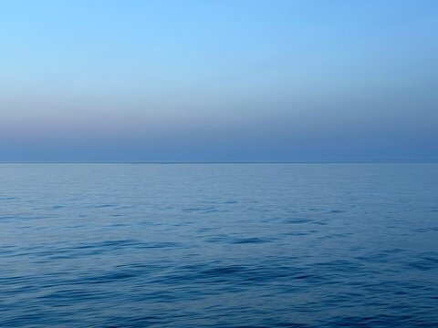 Serene sea calm blue water and sky at evening.