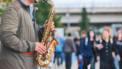 Naklejka premium Street musician playing saxophone performing for crowd outdoors