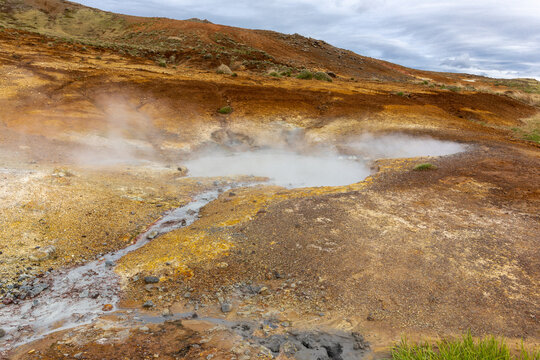 Steaming mud pot and orange sulfur soil in Seltun geothermal area Iceland.