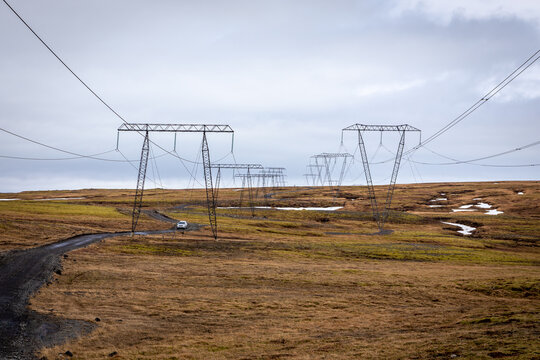 High voltage transmission towers over unpaved dirt road in rural Iceland