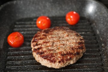 Delicious grilled patty and tomatoes on grill pan, closeup