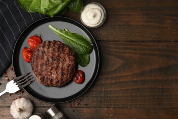 Naklejka premium Delicious grilled meat patty, tomatoes and spinach on wooden table, flat lay. Space for text