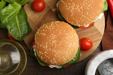 Naklejka premium Delicious burgers with meat patties on wooden table, flat lay