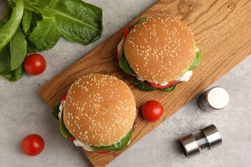 Naklejka premium Delicious burgers with meat patties on grey table, flat lay